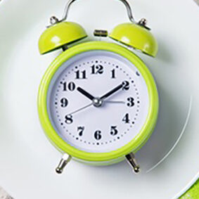 Alarm clock with bells on the plate, lunch time concept, top vie